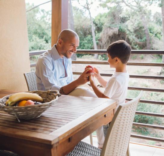 Vater und Sohn spielen mit einem Apfel auf dem Balkon.